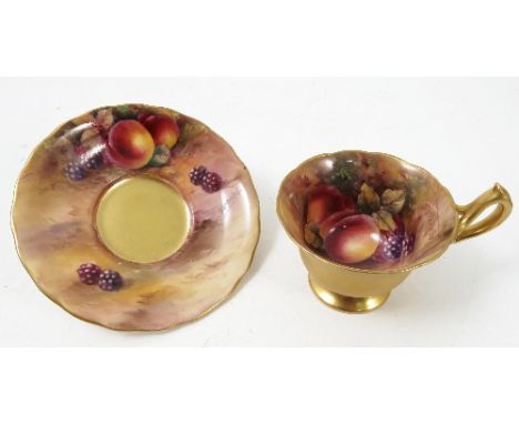 A Royal Worcester pedestal tea cup and saucer, the interior of the cup and saucer hand painted with fruit to a mossy backgrou