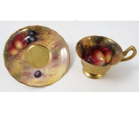 A Royal Worcester pedestal tea cup and saucer, the interior of the cup and saucer hand painted with fruit to a mossy backgrou