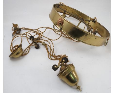A brass weighted light fitting, the circular band decorated with lion masks, having three lights and weighted pulley
