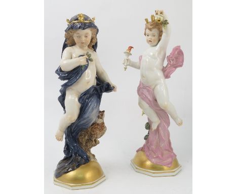 A pair of Meissen figures, emblematic of night and day, modelled as semi naked putti with night having a dark cloak with star