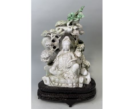 A CHINESE JADE SCULPTURE DEPICTING THE SEATED GUANYIN WITH RUYI SCEPTRE, SURROUNDED BY BAMBOO SHOOTS, BIRD AND FOLIAGE40cm x 