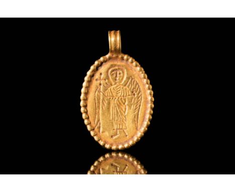 Ca. AD 500 - 700. A Byzantine 20 ct gold oval pendant depicting a standing angel. The angel is dressed in a long robe with sp