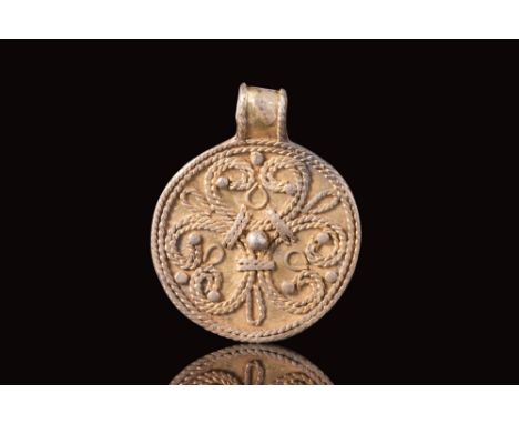 Ca. AD 900 - 1100.A Viking gilt circular pendant with a symmetrical geometric composition, featuring a repeated motif of line