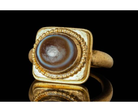 Ca. AD 500 - 600. A Byzantine gold ring with a double-layered rectangular bezel. The bezel secures a banded agate cabochon fr