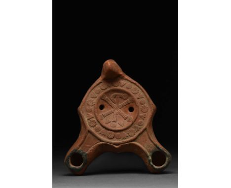 Ca. AD 300 - 400. A mould-made pottery lamp with a deep red colour, except around the nozzle where it has darkened from use. 