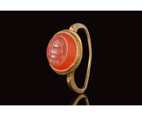 Ca. AD 200 - 500. A Sassanian gold ring with a cylindrical band connected to a rounded bezel securing a carnelian intaglio de