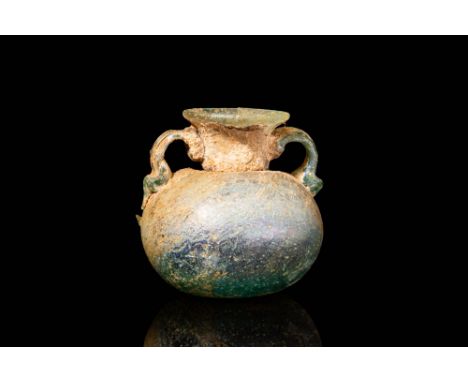 Ca. AD 100 - 300. A Roman pale blue glass amphoriskos with a circular concave base and globular body. The body tapers to a sh