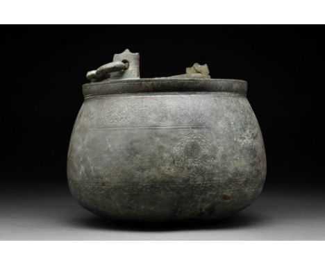 Ca. AD 1100.A rare bronze situla with a scalloped handle, short bulging neck, out-flared body and rounded base. The exterior 