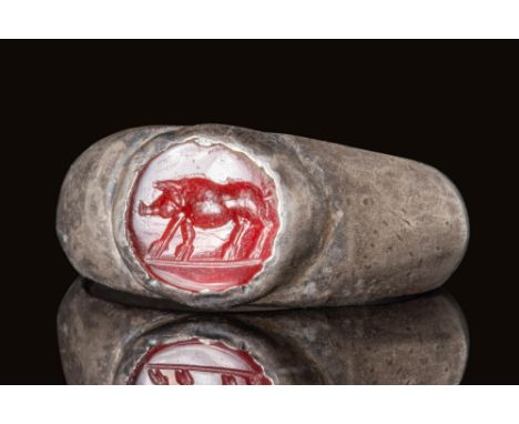 Ca. AD 100 - 300. A Roman silver ring with enlarged shoulders to form a bezel securing an oval carnelian intaglio. The intagl