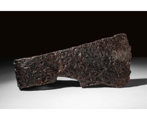 Ca. AD 900 - 1100. A Medieval iron axe head with a short, linear blade bearing a sharpened edge. A black patina with russet a