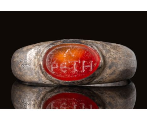 Ca. AD 50 - 200. A Roman silver ring with a round hoop enlarged on the shoulders to form a bezel securing an oval carnelian i