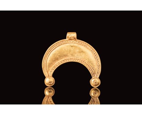Ca. AD 900 - 1100. A Viking gold pendant in the shape of a crescent featuring double gold twisted threads around the borders 