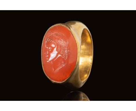 Ca. AD 100 - 300. A Roman gold ring with D shaped band and flattened soulders with a high set oval bezel securing an hellipti