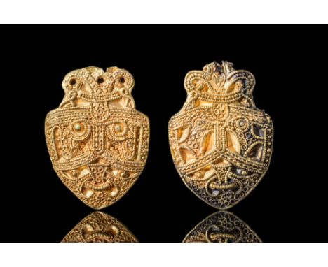 Ca. AD 800 - 1000.A pair of 21 ct gold Viking pendants in the shape of shields. Both pendants depict the face of the god Odin