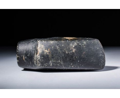 Ca. 5000 - 3000 BC. A dark black stone axe, with an unsharpened blade. It has a hammer shaped butt and socketet long hole in 