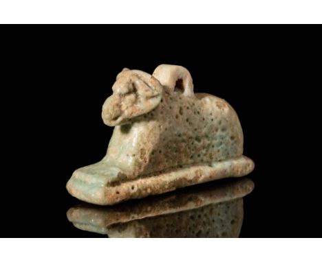 Ca. 664 - 30 BC. A beautiful pale green faience amulet depicting a recumbent Khnum with long and curved horns. Khnum was the 