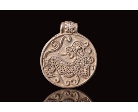 Ca. AD 900 - 1100.An Viking pendant of a discoid form, shaped from a thin sheet of silver. The circular accessory features pl