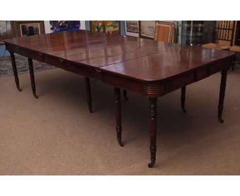 Regency period mahogany extending dining table with moulded frieze and raised on ten ring turned tapering supports with brass