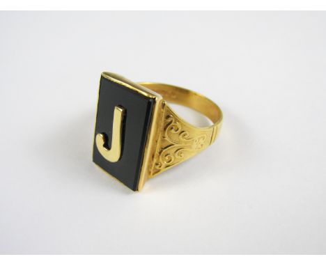 A gentleman's 9ct gold signet ring, the black onyx rectangular face surmounted by the letter 'J', rub set above a shaped and 