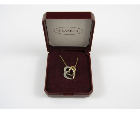 A yellow metal pendant retailed by H. Samuel in the form of two interlocking hearts, the face of each illusion set with diamo