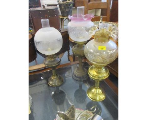 A Victorian oil lamp and two later examples, all with funnels and glass shades 