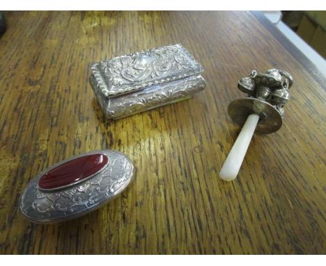 A small silver pill box, a white metal child's rattle with mother of pearl handle, and a silver oval pill box with inset Corn