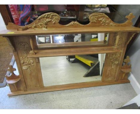 A light wood overmantel mirror with applied plaster scrolled leaf and floral decoration 