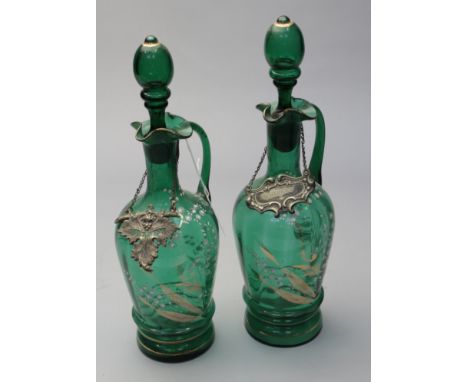 A pair of Victorian green glass spirit decanters and stoppers, each with wavy rim and elongated loop handle, the bodies decor