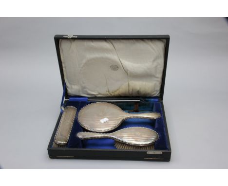E H Lawley and Sons, a presentation cased three piece silver backed mirror and brush suite, each with monogram and engine tur