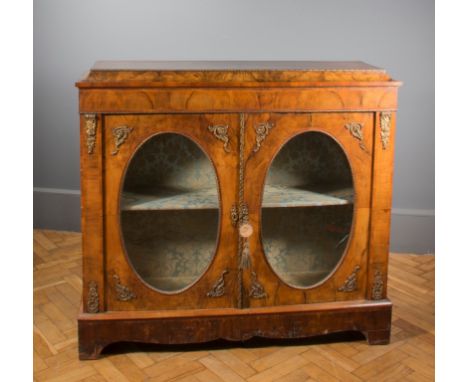 A 19th century walnut and gilt metal mounted credenza, the caddy top above a pair of oval glazed cupboard doors enclosing two