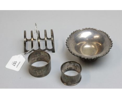 A small collection of silver items, to include a four slice melba toast rack, two silver serviette rings and a small bon bon 