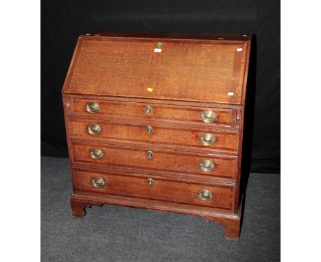 A George III oak bureau, the crossbanded fall enclosing a strung fitted interior over four graduated long drawers with oval b