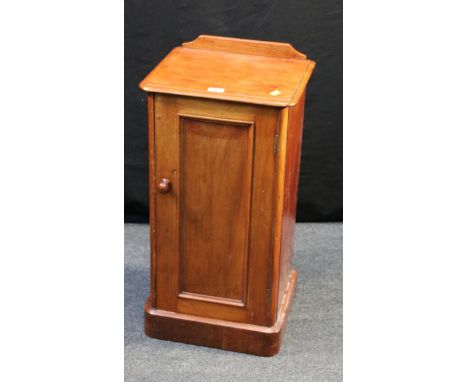 A Victorian mahogany pot cupboard with low upstand over a moulded edge top and panel door with knop handle enclosing single s