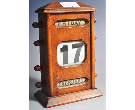 A 1920's vintage oak desk perpetual calendar having a raised top with four spindles to each side with day, date and month adj