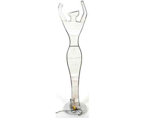 A contemporary free standing floor lamp light in the form a woman having a polished metal frame with arms held over her head 