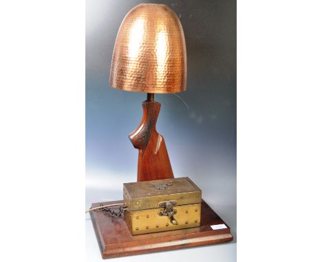 A vintage 20th Century home made gun stock / butt gun desk / table lamp light having a panel beaten conical copper shade with