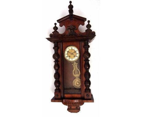Early 20th century walnut cased Vienna type wall clock, the overhanging cornice surmounted by an elaborate and shaped archite
