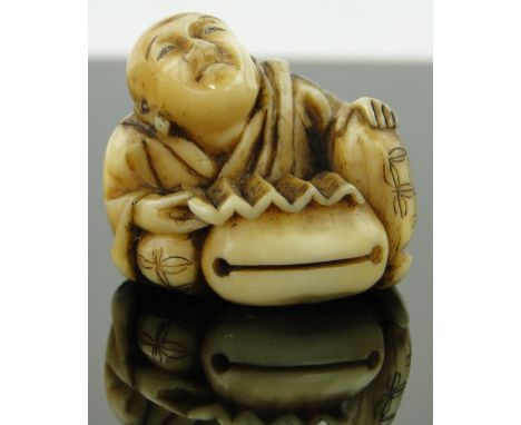 A 19th century Japanese ivory netsuke
depicting a seated man reading, 1.25" across.