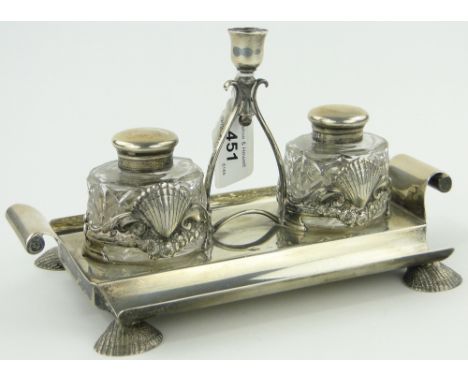 A Victorian silver desk stand,
with central candlestick flanked by cut-glass inkwells on shell feet, London 1889, length 23cm