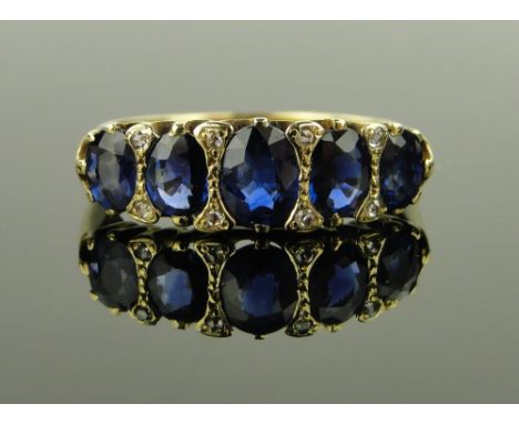 An 18ct gold 5 stone graduated sapphire ring,
with small diamond points, setting width 22mm, size R.