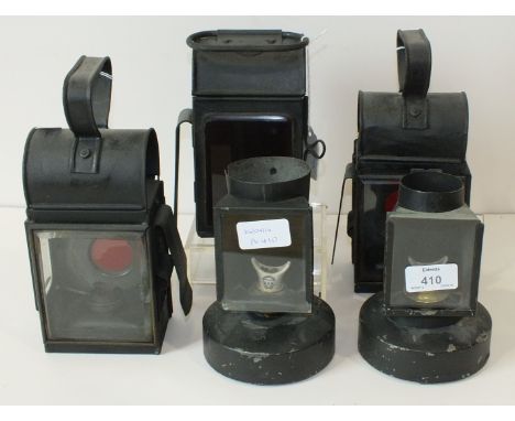 Two black-painted metal hand lamps with burners and red filters, 22cm high, another similar lamp and two other oil lamps, (5)