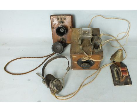 A cats whisker type radio receiver with head set, a wooden mounted wall telephone speaker and ear piece, and a bell.