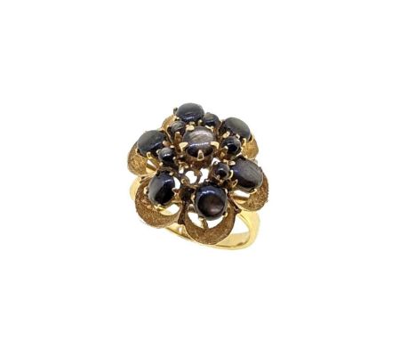 A star sapphire cluster ring, floral cluster set with round and oval cabochon black star sapphires (one lacking), head diamet