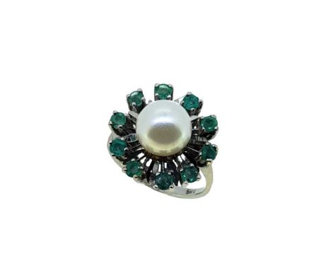 A pearl and emerald ring, central 7.8mm cultured pearl, surrounded by ten claw set round faceted emeralds, tapered shoulders,