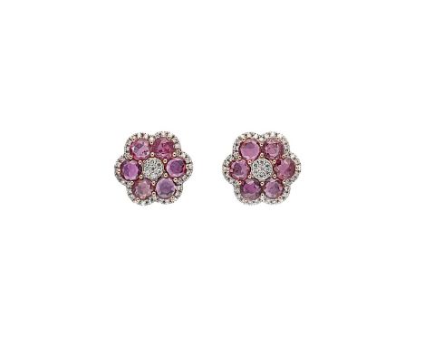 A pair of ruby and diamond cluster ear studs, each with a central cluster of round brilliant cut diamonds, surrounded by six 