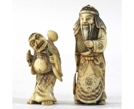 An early 20th century Japanese carved bone netsuke, modelled as a standing figure, holding a mask, 4cm high, together with an