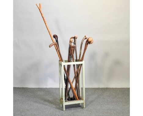 A collection of walking and shooting sticks, in a painted wooden stick stand, 66cm high