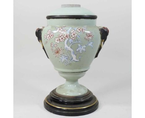 A 19th century celadon glazed oil lamp base, painted with blossom and having elephant mask decoration, 28cm high