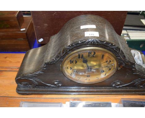 A large wooden mantel clock with brass dial