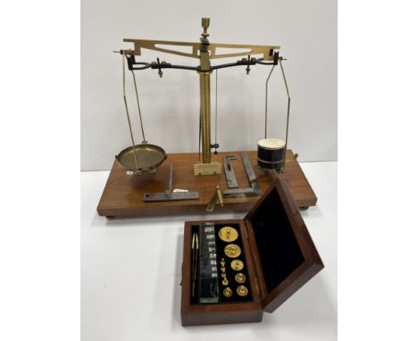 A pair of brass precision scales on mahogany platform base, together with a set of precision weights and tongs, bearing ivori